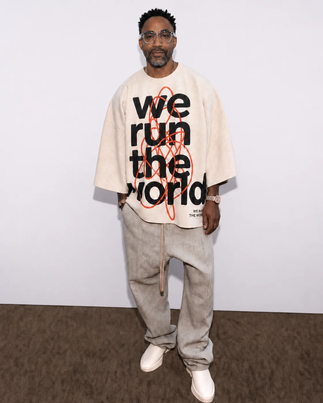 Man wearing the cream oversized We Run the World tee and glasses
